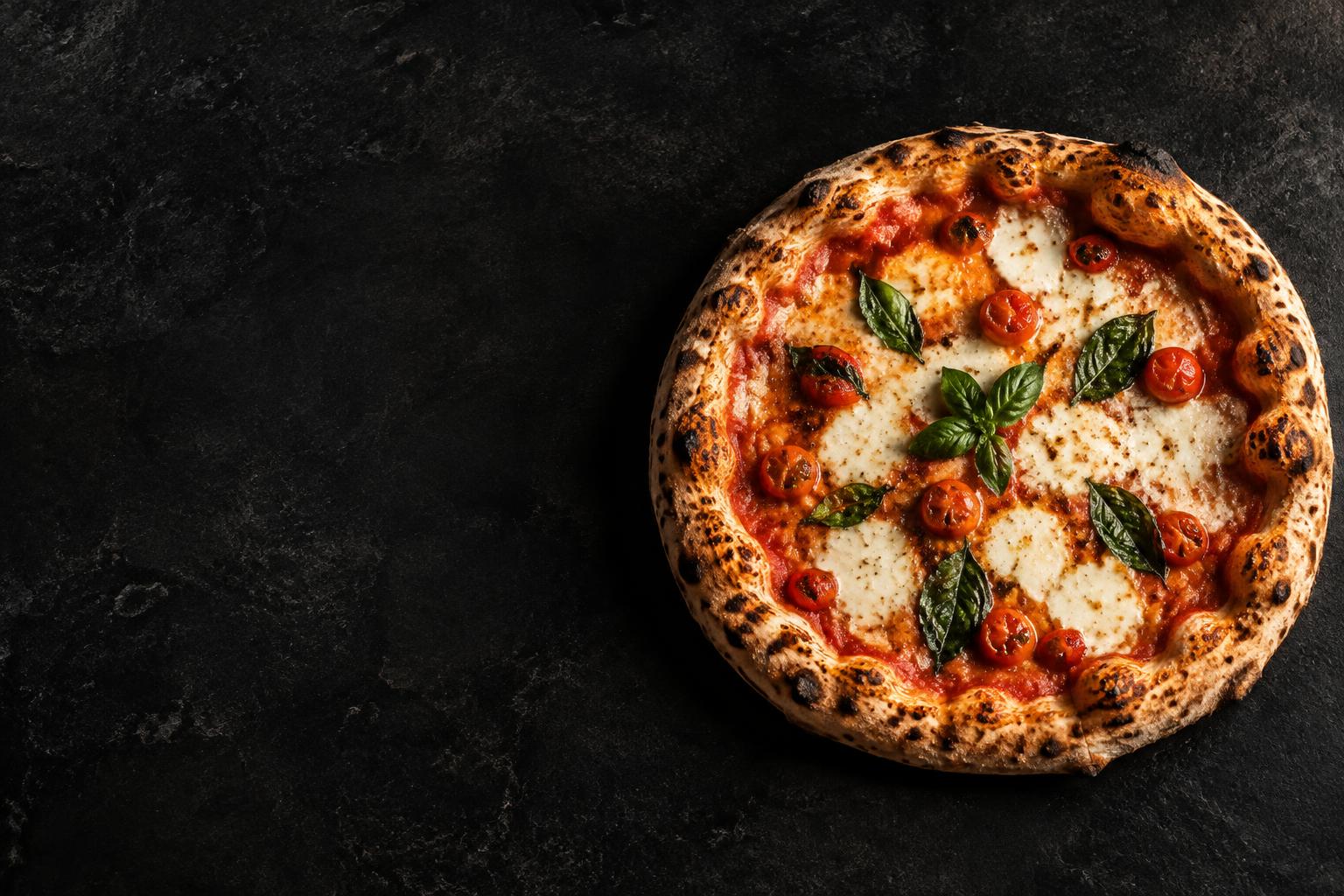 Nybakad pizza med mozzarella, tomat och basilika